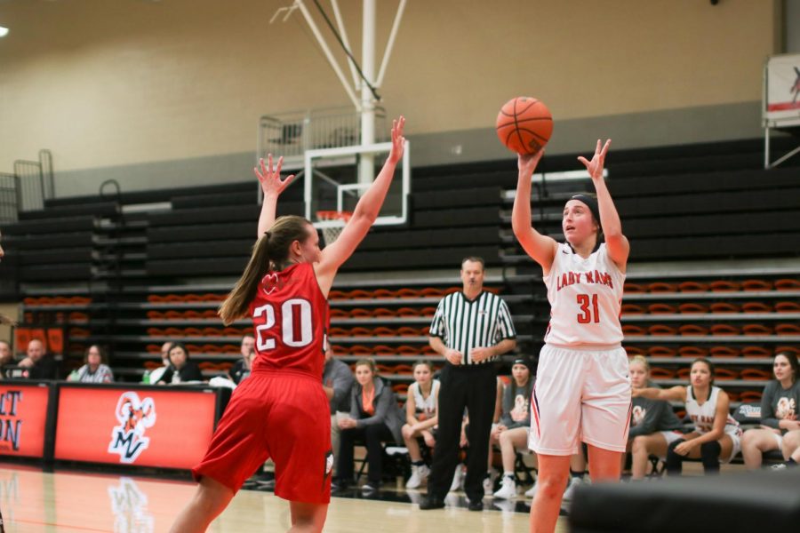 Olivia Ryan, 19 shoots a three-point shot while a Flaming Hearts defender attempts a block. 