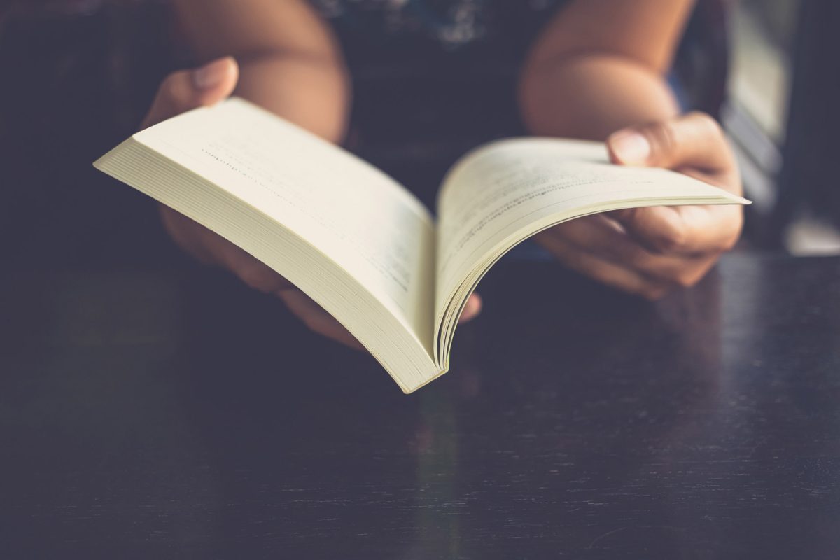 Woman place her arms on her lap and open book to read